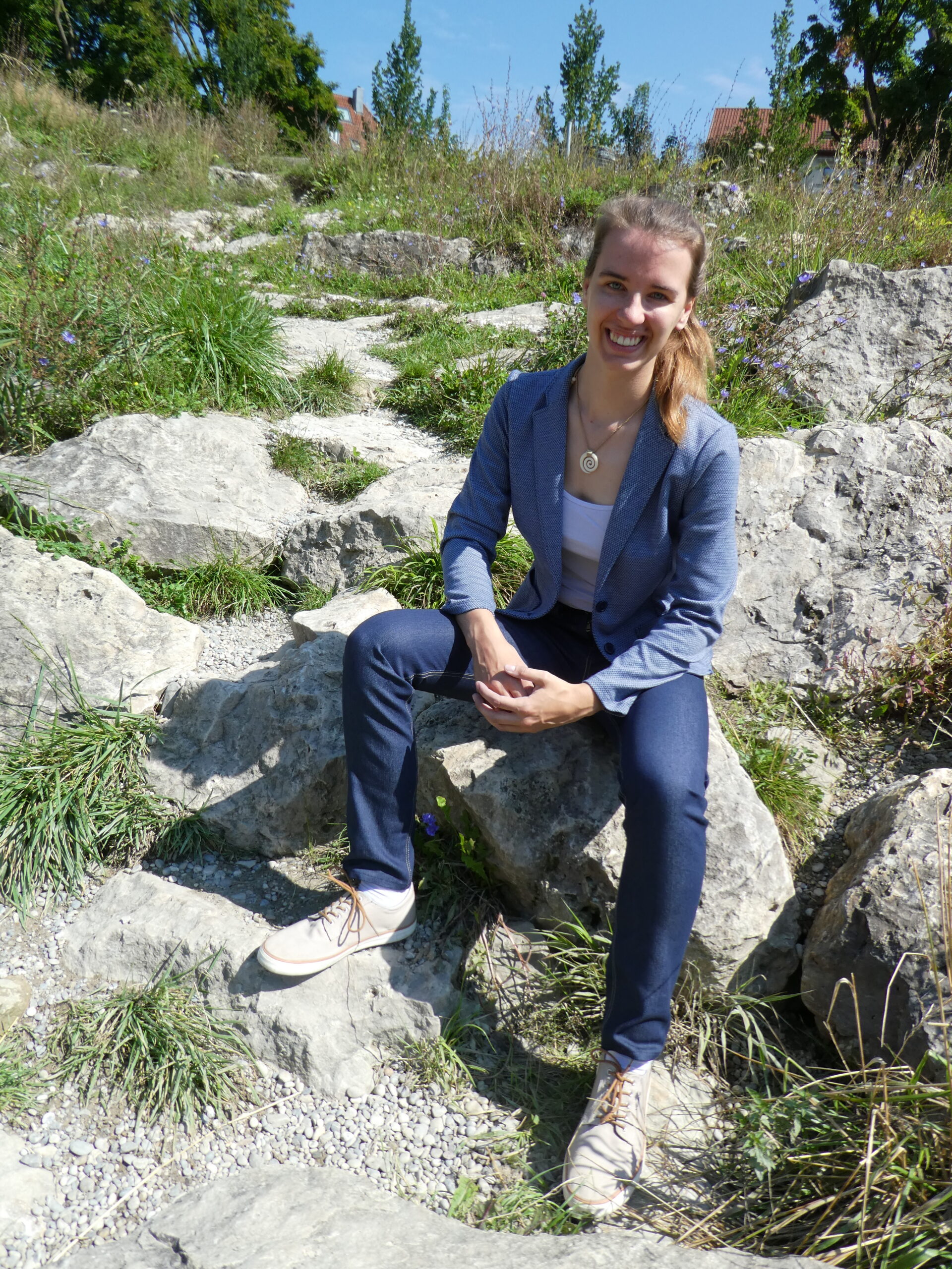 Lia von Real Pockets auf Steinen sitzend