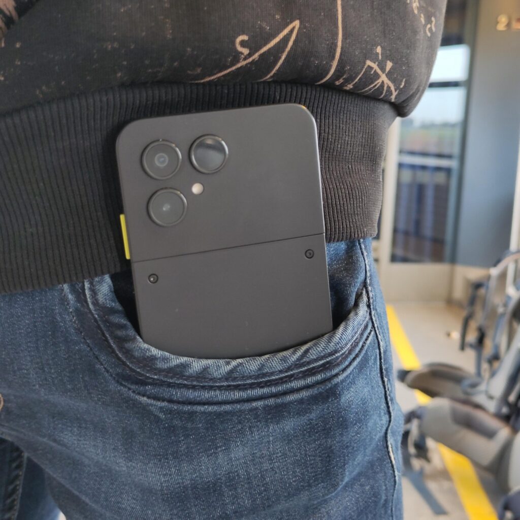 Das Handy steckt in der vorderen Hosentasche einer Frauenjeans und schaut zur Hälfte raus.